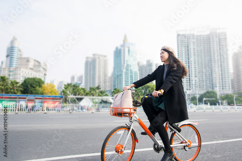 Fototapeta Naklejka Na Ścianę i Meble -  Asian office lady riding bicycle through urban area