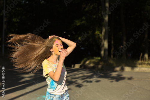 Laughing brunette woman with wind in hair playing with dry paint Holi