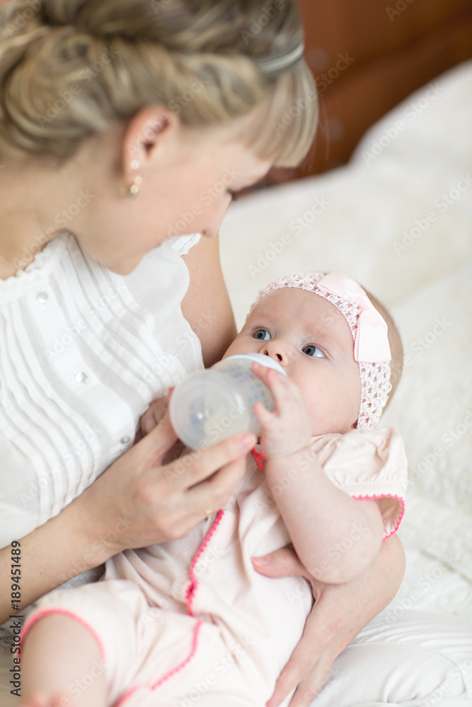 Mom holding and giving milk formula to baby from bottle Mom holding and giving milk formula to baby from bottle