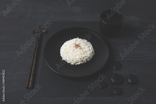 rice with cup of tea and chopsticks on black table