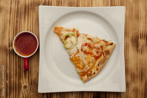 a piece of vegetarian pizza on a plate served with ketchup