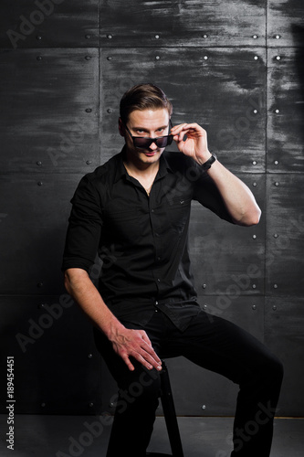 Studio portrait of stylish man wear on black shirt and glasses against steel wall.