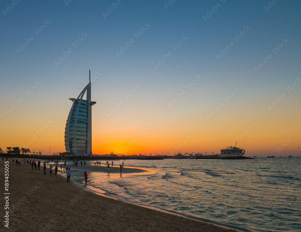 Fototapeta premium People waiting for new year celebration at the beach in last day of the year. The world's first seven stars luxury hotel Burj Al Arab and Dubai Marina in background 