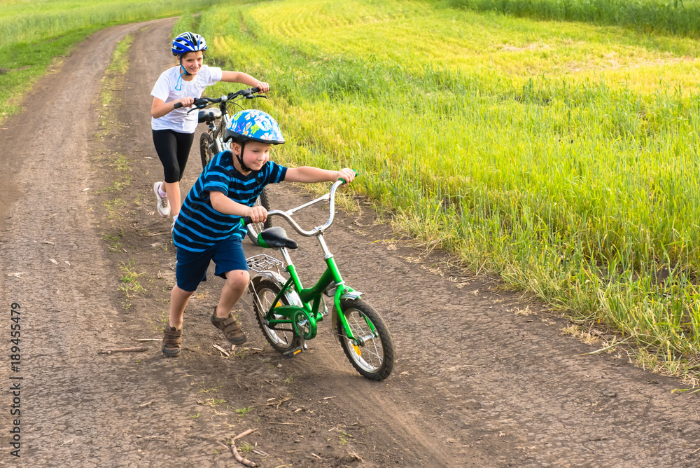 Sporty kids walking uphill with bikes Sporty kids walking uphill with bikes