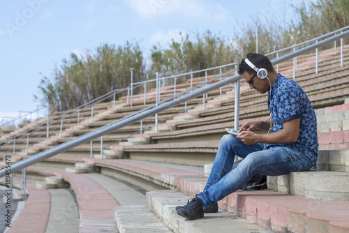 Happy attractive man listening music and typing phone