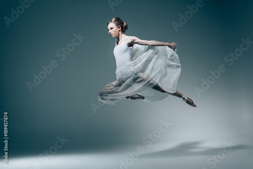 attractive ballet dancer jumping in white dress