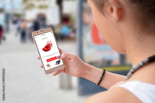 Woman buy online with shopping app on smart phone. City street in background.
