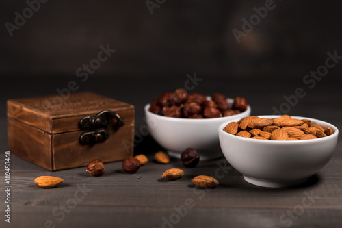 Two white cups filled with nuts, almonds and hazelnuts and a wooden casket photo