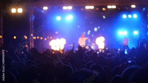 Excited people waving hands up in air, enjoying music at concert