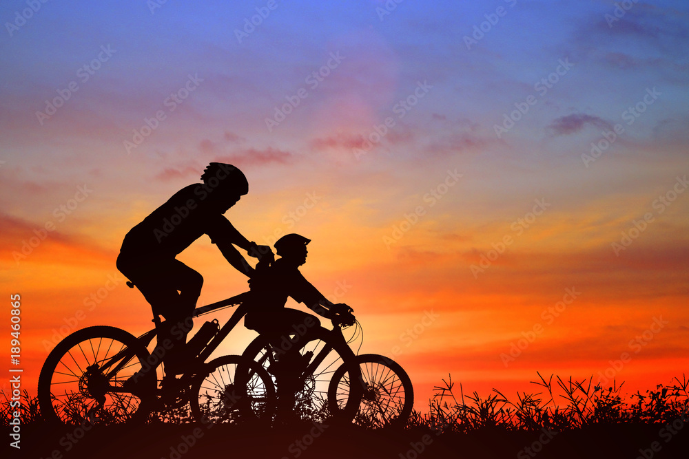 Obraz premium Silhouette man and bike relaxing on blurry sunrise background