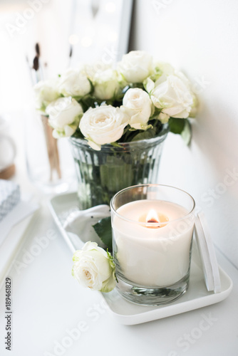 White room interior decor with burning hand-made candle and bouq