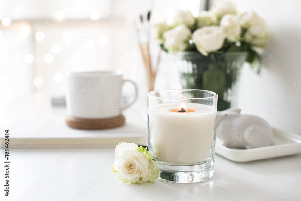White room interior decor with burning hand-made candle and bouq White room interior decor with burning hand-made candle and bouq