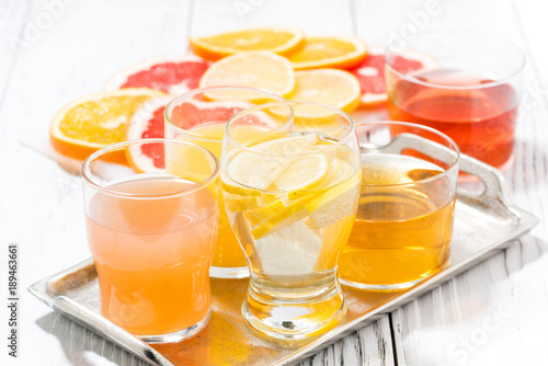 assortment of fresh citrus juices in glasses on white table, closeup
