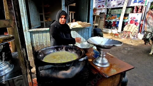 CAIRO, EGYPT - DECEMBER 21, 2017: The cook prepares fava bean falafel (taameyya), using deep fryer, in tiny street kitchen, Al Muizz street, Khan El Khalili Bazaar, on December 21 in Cairo. photo