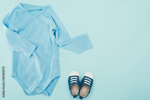 top view of baby bodysuit and shoes isolated on blue © LIGHTFIELD STUDIOS