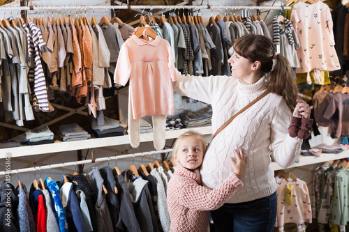 Pregnant female and small daughter choosing clothes © JackF