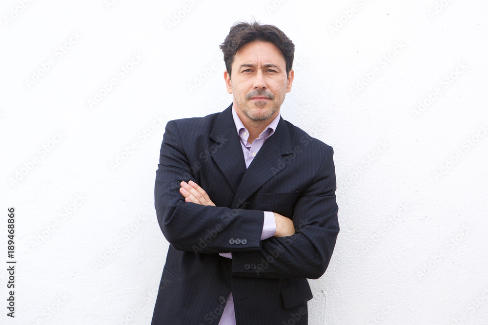 serious older businessman standing with arms crossed against white background serious older businessman standing with arms crossed against white background