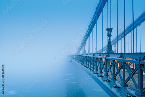 Szechenyi chain bridge in heavy blue fog with no visible coast. Budapest photo