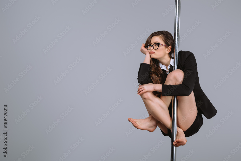 bored young businesswoman in eyeglasses hanging on pole on grey - obrazy, fototapety, plakaty 