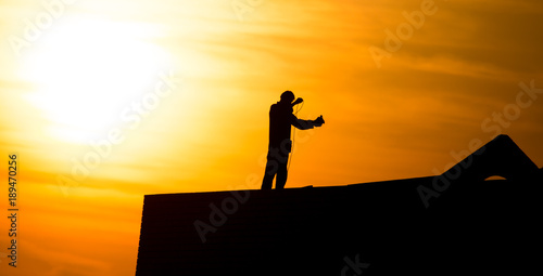 Man at the house under construction at sunset