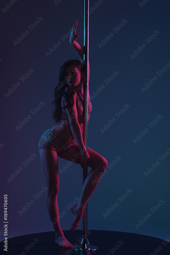 beautiful young female dancer posing with pole and looking away on blue - obrazy, fototapety, plakaty 