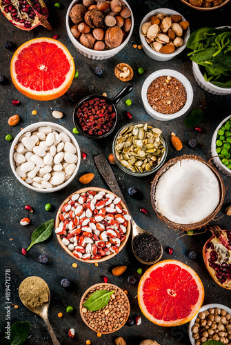 Set of organic healthy diet food, superfoods - beans, legumes, nuts, seeds, greens, fruit and vegetables. Dark blue background copy space top view
