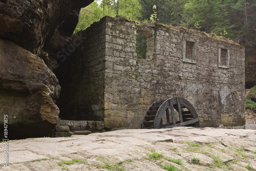 Wooden waterwheel by old castle in forest photo