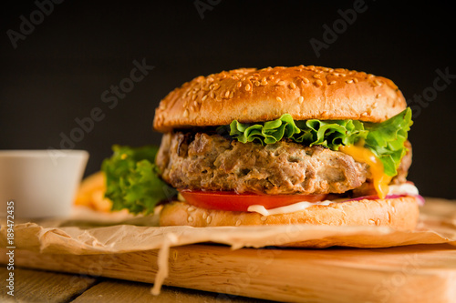 Classic burger with tasty beef  salad  sauce and tomato on dark background. American food