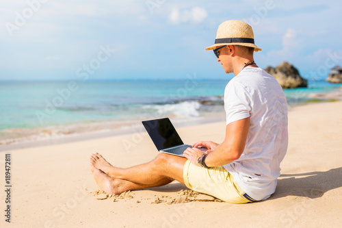 Young man working with laptop computer on the beach