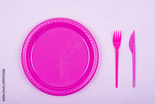 Plate, fork, and pink plastic knife on pink background. Children's celebration Mockup.