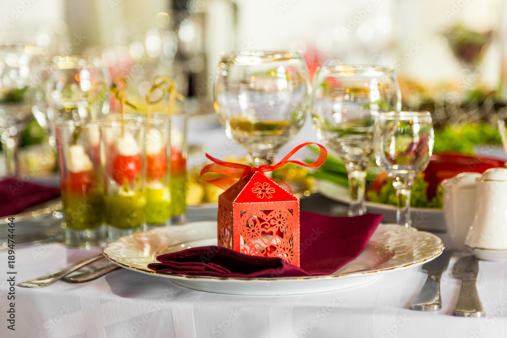 Banquet table, there is a red box with a gift on the plate.