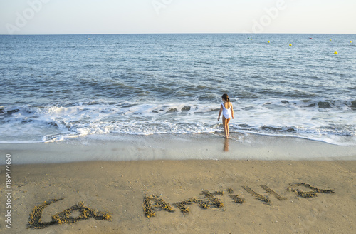 Child girl enjoys at Islantilla sea shore. Over the sand is written La Antilla photo