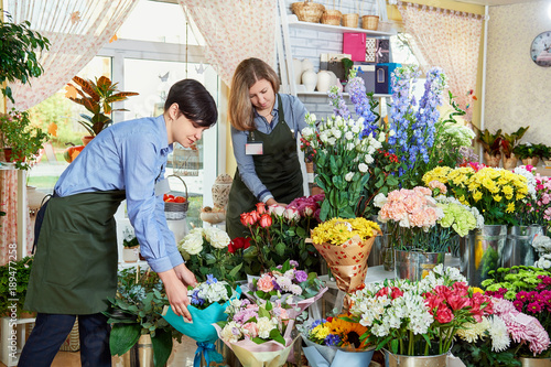 Women working in flower shop.happy woman or gardener taking care of flowers in shop.