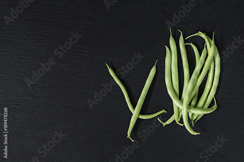Pods fresh green beans on a black stone surface.  Top view  copy space. Healthy eating concept.