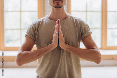Relaxed young man doing yoga and meditating in studio