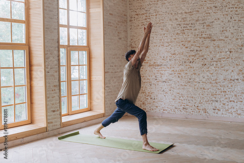 Relaxed young man doing yoga and meditating in studio