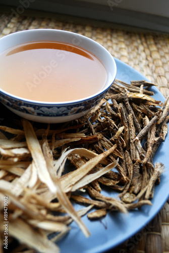 Bowl of chinese herb tea with dried assorted roots aside. photo