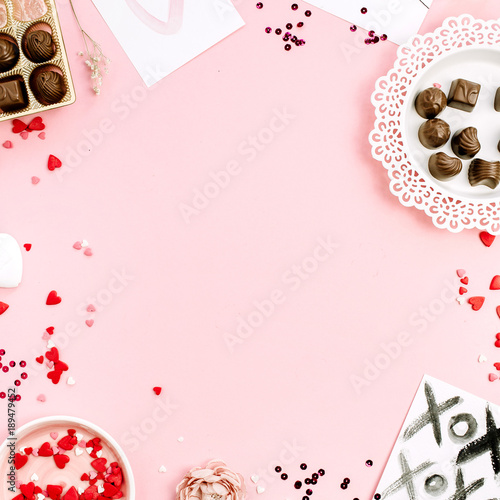 Frame of chocolate candies, heat symbols on pale pink background. Flat lay, top view Valentine's Day or Love concept.
