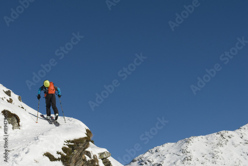 Concept  skier practice ski mountaineering  alta mountains  walking in snow  alone man  adventurous  dangerous sport  climb mountain  technical equipment  having fun in powder  sun  winter  Swiss