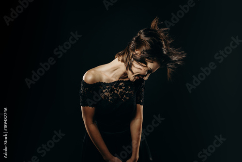 Artistic portrait of a young beautiful woman. Full length photo of fashionable girl in dark dress on big black background. Studio. Low Key. Fashion. Beauty. Advertising. She looking outside