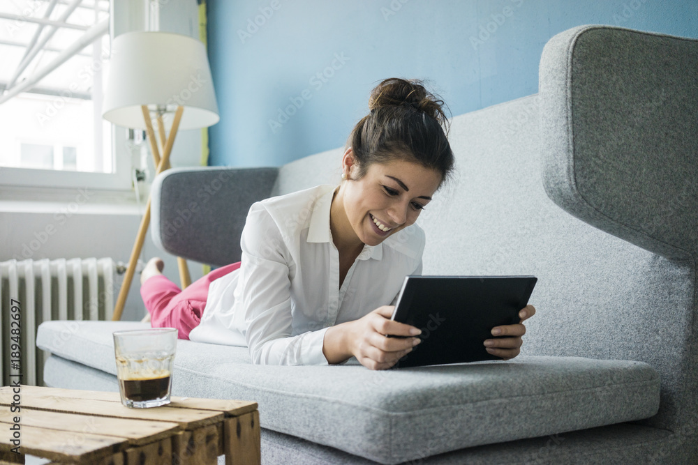Portrait of laughing woman relaxing on couch with tablet Portrait of laughing woman relaxing on couch with tablet