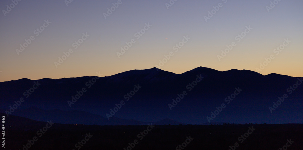 Sunrise or sunrise over mountains silhouette with blue sky background. Panoramic view, banner.