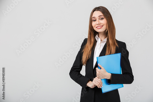 Cheerful businesswoman holding folder and smiling to camera