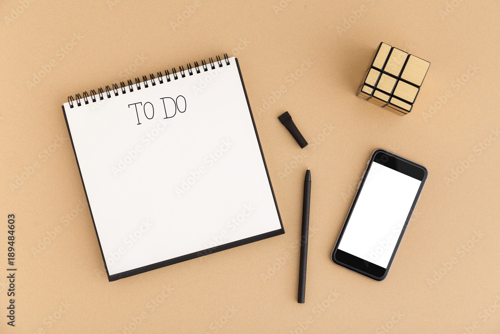 Notebook with to do text smartphone and Rubik's Cube is on the office desk table with supplies. Top view, flat lay. Notebook with to do text smartphone and Rubik's Cube is on the office desk table with supplies. Top view, flat lay.