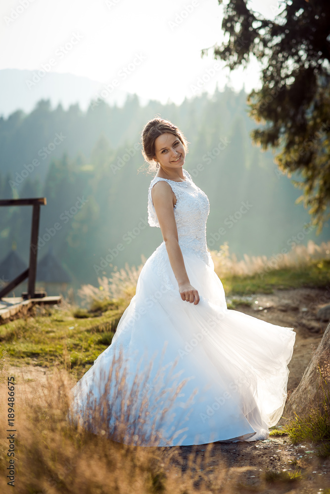 Full-length wedding shot of the beautiful smiling bride in the long dress spinning round in the forest. Full-length wedding shot of the beautiful smiling bride in the long dress spinning round in the forest.