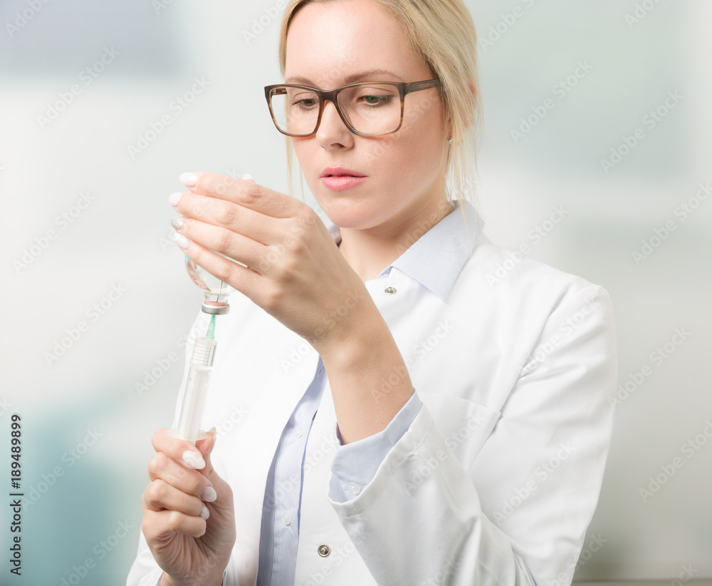 Junge hübsche Ärztin zieht Serum in Spritze auf Junge hübsche Ärztin zieht Serum in Spritze auf