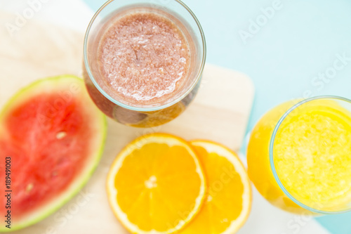 Tropical Smoothie Cocktail with fresh watermelon, orange, grapes and bananas. Light blue background, top viewHealthy food, Diet, Fitness, Dessert Concept