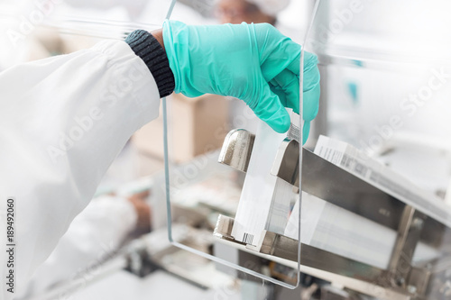 Photography Hand placing labels into a label inserting machine in Pharmaceutical manufacturing process
