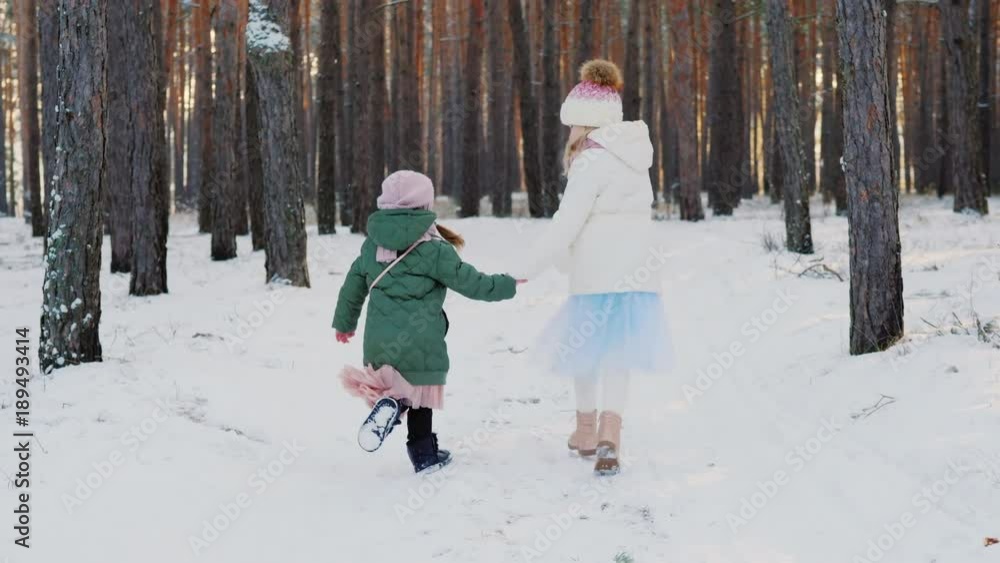 Back view: Two carefree little girls running through the winter forest. Steadicam shot Back view: Two carefree little girls running through the winter forest. Steadicam shot