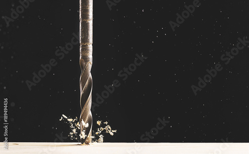 drilling a tree with flying chips on a black background